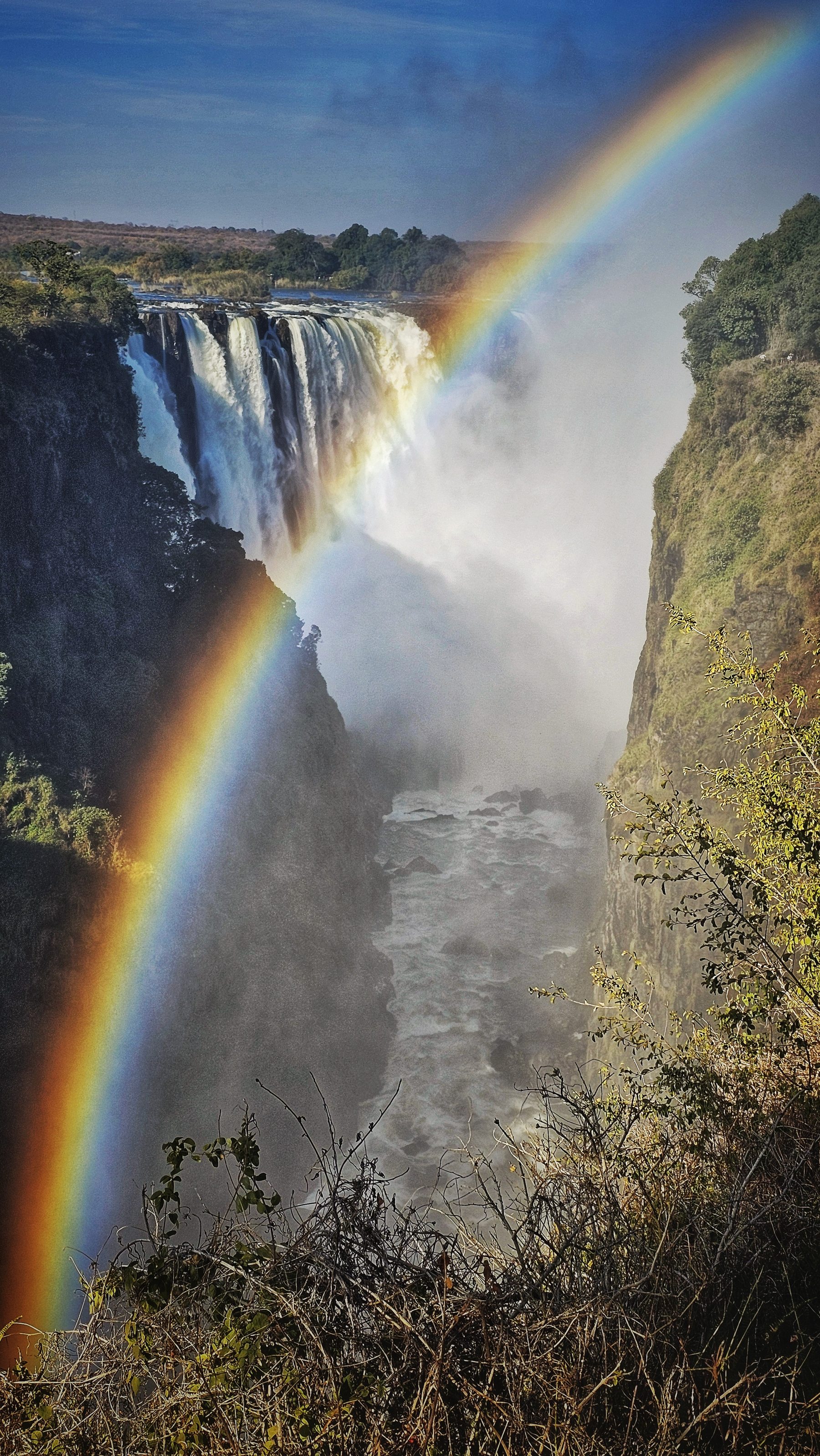 Tęcza w bryzie i skalne ściany wąwozu przy Victoria Falls